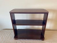 Front view of compact Art Deco walnut shelf showing two shelves and smooth dark finish.