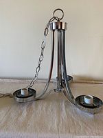 Chrome three-armed ceiling light fixture shown laid flat with chain and bulb sockets visible