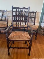 Four oak chairs including one arm chair and three side chairs arranged against wall