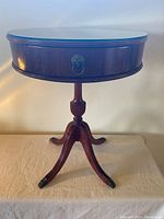 Front view of the round mahogany drum table with glass top on pedestal base with claw feet.