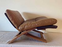 Side view of ottoman showing angled wood frame and padded leather cushions