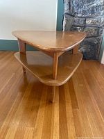 Front angle view of the mid-century two-tier triangle coffee table, showing the shape, legs, and lower shelf.