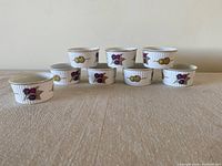 Set of eight white Royal Worcester Evesham ramekins arranged in two rows showing the decorative fruit motif exterior design.