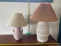 Both vintage ceramic lamps on wooden surface showing scale with measuring tape behind.