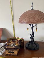 Quoizel twig design lamp next to disassembled cuckoo clock body with ruler for scale
