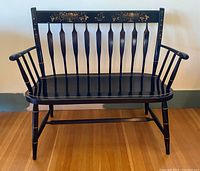 Front view of black lacquer Windsor style bench showing spindled back, armrests and seat