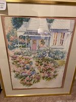 Front view of framed watercolor painting with pastel English garden scene and gold-tone metal frame