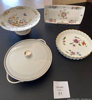 Photo showing all four dishware pieces on a table including covered serving dish, cake stand, rectangular plate and quiche dish.