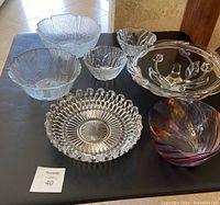 Seven glass bowls of various sizes and patterns displayed on a black surface.