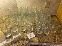 Group photo showing multiple clear drinking glasses of various sizes and styles arranged on countertop.
