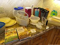 Overview of plastic kitchen items including covered beverage pitchers, floral pitchers, covered cups, storage containers, measuring cup, dishwasher baskets, and storage bags.