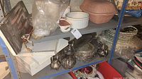 Metal shelving unit showing items including the silver-plated tea and coffee pots, serving dishes, and bathroom accessories