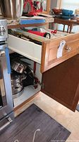 Drawer open showing pots and pans stacked and utensils in organizer trays