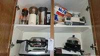 Photo showing kitchen cabinet with various kitchen appliances including Wolfgang Puck Swivel Baker, Oskar food chopper, Multinex food grater, coffee brewer, coffee filters and other items.