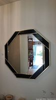 Front view of the octagon wall mirror showing the black and gold geometric frame design