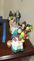 View of five Royal Doulton figurines arranged in a line on a table, various poses and characters