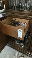 Dresser drawer with assorted silver and silverplated flatware and utensils including spoons and forks.