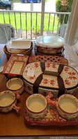 Full lot view showing various ceramic dishes arranged on a table including soup crocks, baking dishes, a bread bowl, and woven storage basket.