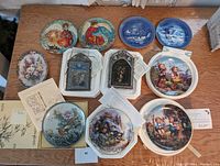Top view of the 11 decorative collector plates arranged on a table showing various themes including religious, nature, and children.