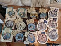 Top view of fifteen themed collector plates arranged to show detailed artwork and accompanying certificates.