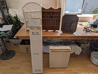Five display shelves and cases arranged on table and floor including two wooden display cases, one white shelf, and two boxed items