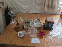 Full view of the lot on a wooden table with the glass candle holder with wooden base and assorted glass items including candle holders and decorative pieces.