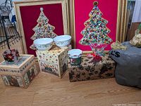 Wide view of Christmas-themed lot items including framed artworks, bowls, and boxes on floor.