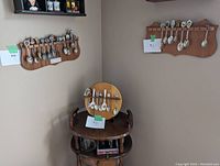 Wide view of three wooden racks in a corner wall, each holds multiple collector spoons of varying designs.