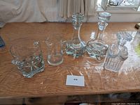 Photo of all five crystal decanters and pitchers on wood table.