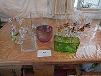 Full lot displayed on a wooden table showing all glass items including Hard Rock Cafe glasses and the glass handbags and containers