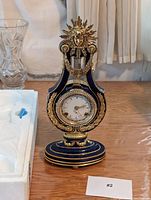 Full view of blue enamel and gilt metal lyre clock on table