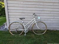 Full left side view of the white Norco bicycle showing frame, wheels, saddle, pedals, and handlebar.