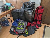 Image showing full lot of travel bags including backpacks, soft bags and rolling suitcases arranged on floor in front of wooden cabinets.