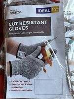 Close-up photo of Ideal Pro branded packaging of cut resistant gloves showing product features such as EN388 Cut Level 5, superior cut and slash protection, and that they are durable & washable.
