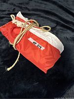 Photo of a folded large Canadian flag, tied with a natural fiber rope, laid on a black fabric background