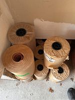 Top view photo showing 10 rolls of brown kraft-style paper for meat packaging with black plastic inner cores.