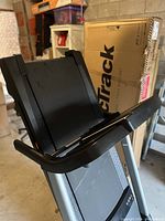 Full view of the folded NordicTrack treadmill with running deck lifted, showing the textured belt and control panel area.