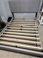 Bed frame showing wooden slats base with visible damage, missing or broken slats.