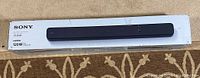 Sony HT-S100F sound bar in its box showing the product image and brand.