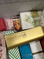 Box containing various vintage perfumes and soaps including Perry Ellis 18 Sensual, Natalia perfume, and flower-themed soap boxes.