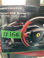 Box displaying Ferrari 458 Spider branding, showing racing wheel and pedal set images, with some wear and tear visible on corners.