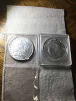Loose and cased 1896 Morgan dollars side by side on fabric background