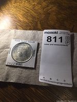 Full coin in cardboard holder with label Peace Silver Dollar and date 1922.