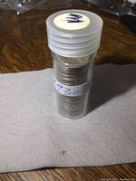 Plastic tube filled with stacked Canadian 5 cent coins from the 1930s, labeled with "1930" on the tube.