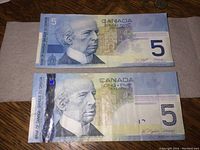 Two Canadian $5 bills side by side showing front design differences, with 2006 bill having a holographic security strip.