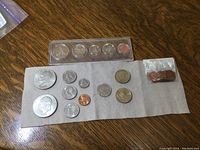 Top-down view of multiple coins on cloth and hard plastic Panama coin set, also small packet of Canadian pennies.