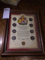 Framed Canadian Commemorative Collection coin set showing overall layout with 8 silver dollars and 1 loonie, within a stained and moisture-damaged 9x12 wooden frame.