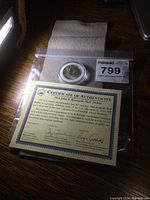 Photo showing the 1964 JFK half dollar coin in a round hard plastic case along with the Certificate of Authenticity.