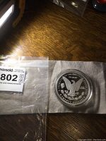 Photo showing the coin in hard plastic case with a MaxSold tag nearby.