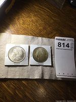 Two Morgan dollars in white cardboard coin flips with lot tag